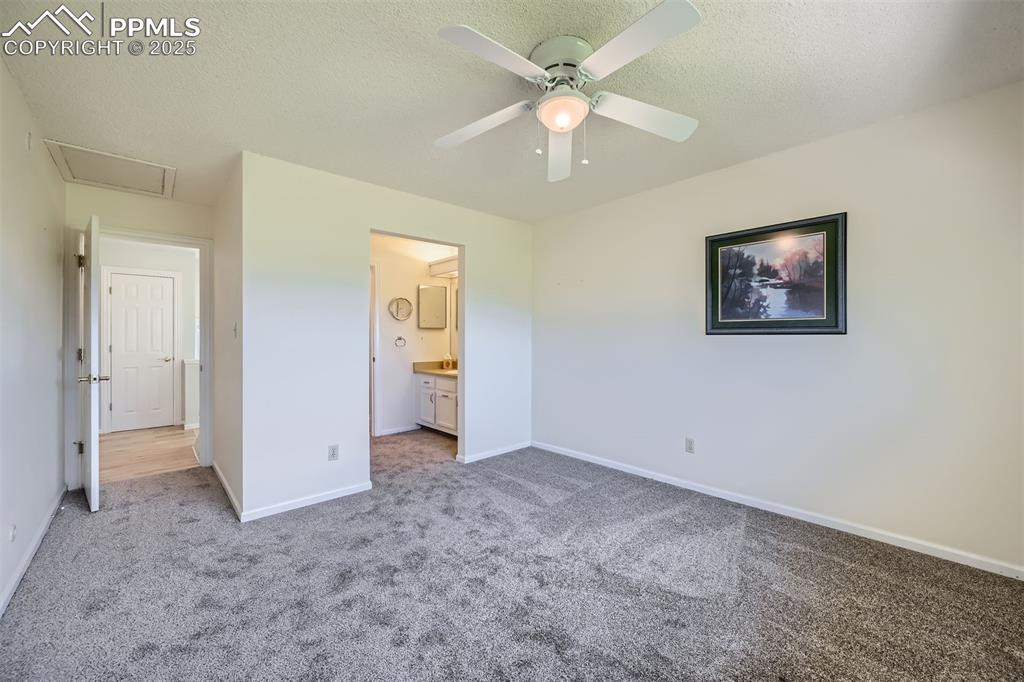 Image 22 of 29: Unfurnished bedroom with carpet flooring, a textured ceiling, ensuite bathr