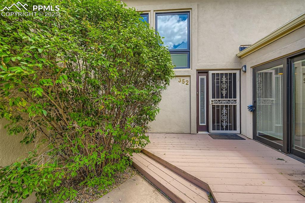 Image 3 of 29: View of exterior entry featuring stucco siding and a wooden deck