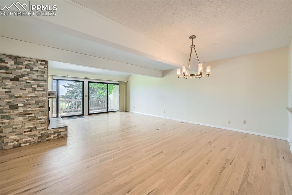 Image 6 of 29: Living room featuring a chandelier, light wood-style flooring, and a textur