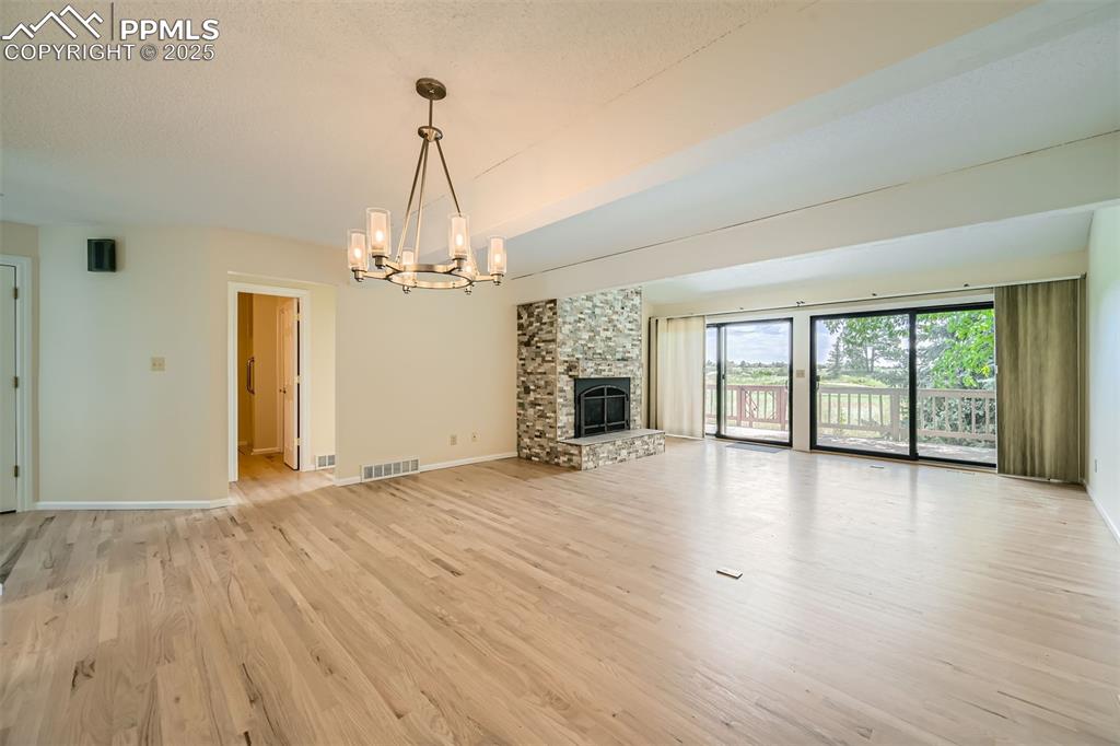Image 7 of 29: Unfurnished living room with a chandelier, light wood-type flooring, and a