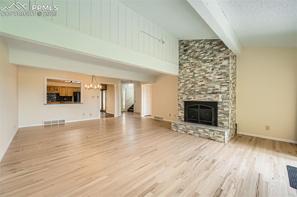 Image 8 of 29: Unfurnished living room featuring a stone fireplace, wood finished floors,