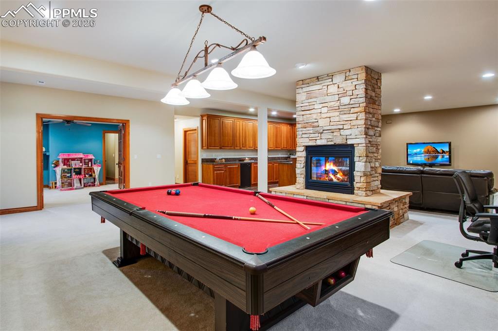 Image 29 of 42: Game area in the basement with a double sided fireplace and access to the s
