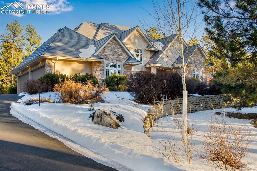 Image 4 of 42: Front of the house with mature landscaping and retaining wall