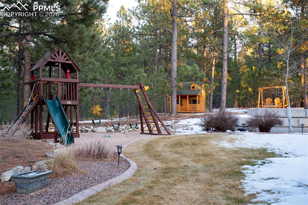 Image 8 of 42: Backyard includes a play structure, play house, in-ground trampoline, and o