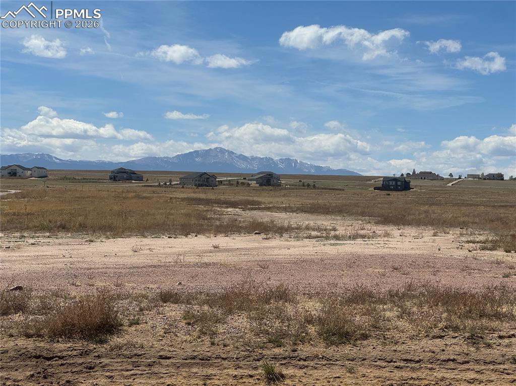 Image 2 of 9: Expansive lot with distant mountain views under a bright, cloudy sky