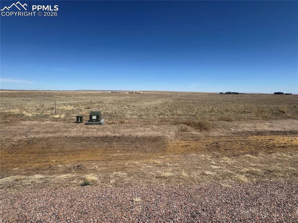 Image 4 of 9: Expansive open land featuring diverse ground cover and a clear blue sky