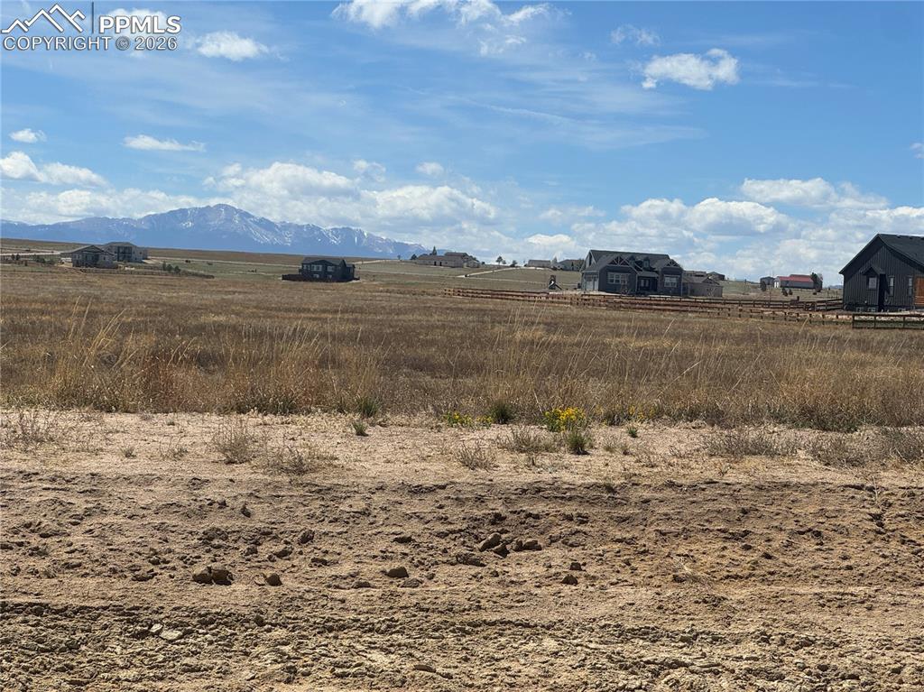 Image 5 of 9: Expansive land with distant mountain views, featuring a clear sky with scat