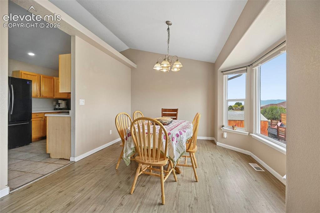 Image 11 of 32: Dining area featuring wood-finish flooring, a vaulted ceiling, and a multi-