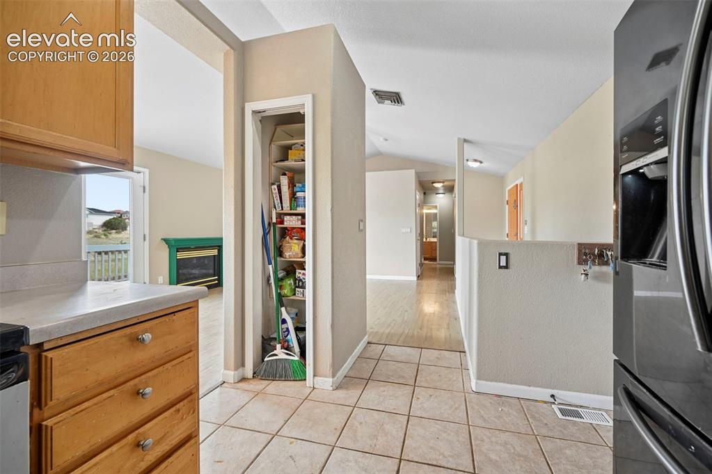 Image 12 of 33: Kitchen area featuring wood-finish cabinetry, light-toned countertop, and t
