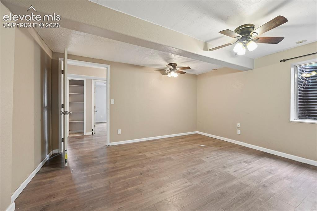 Image 14 of 32: Spacious interior room featuring wood-finish flooring, neutral wall tones,