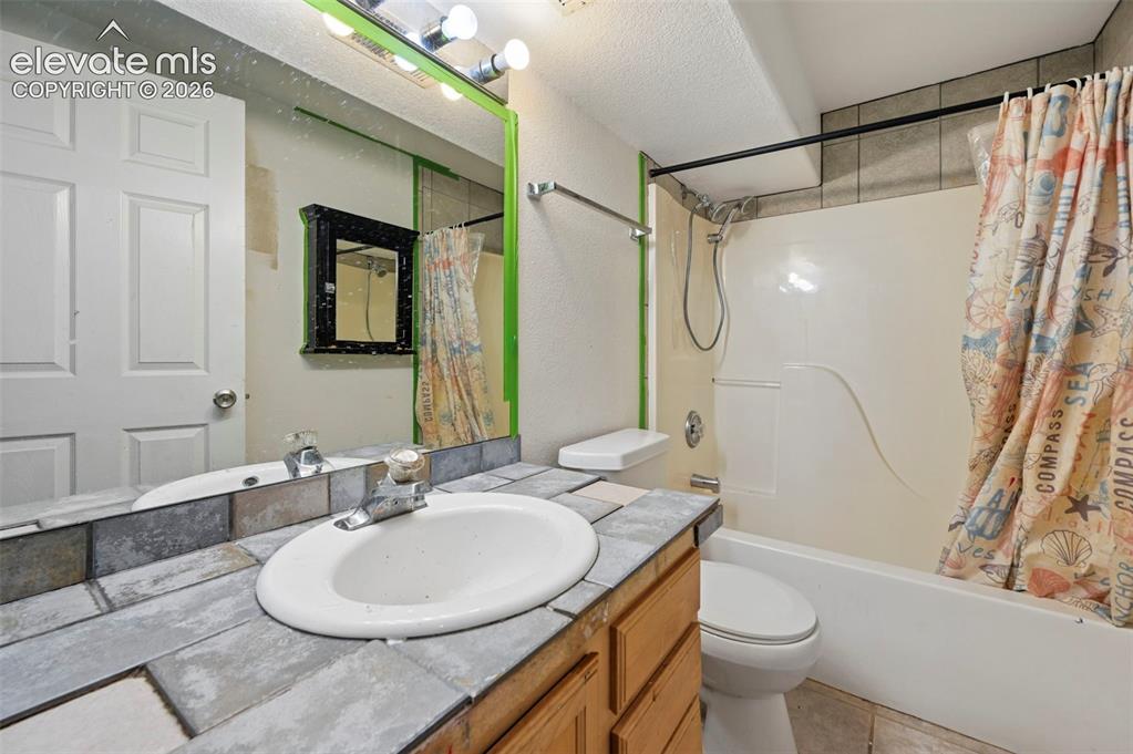 Image 17 of 33: Bathroom featuring a vanity with a drop-in sink and tiled countertop, an in