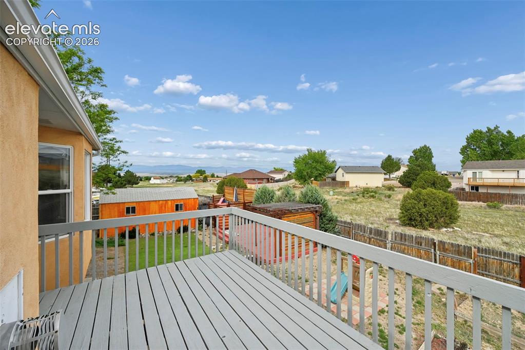 Image 18 of 32: Wood-tone deck with light gray railing, featuring a surrounding landscape w