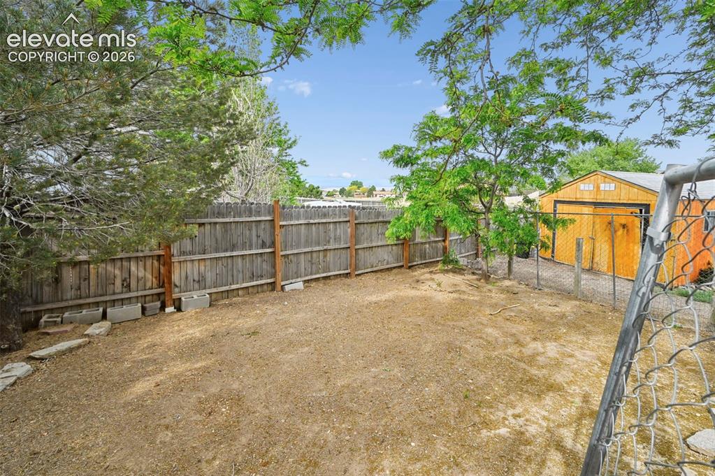 Image 23 of 32: Spacious backyard area featuring a wood privacy fence and mature trees