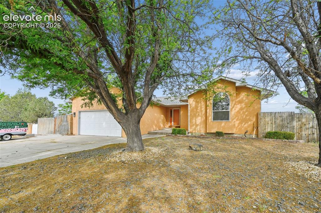Image 24 of 32: Saffron stucco exterior featuring an arched window, a two-car garage, and a