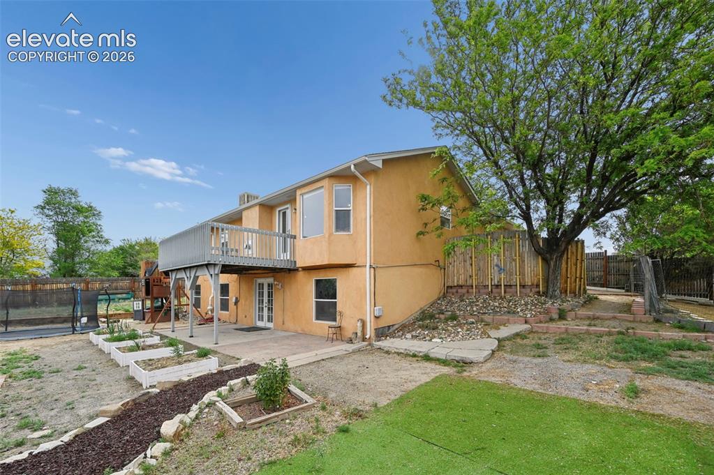 Image 26 of 33: Rear exterior featuring a second-story deck, ground-level patio, multiple r