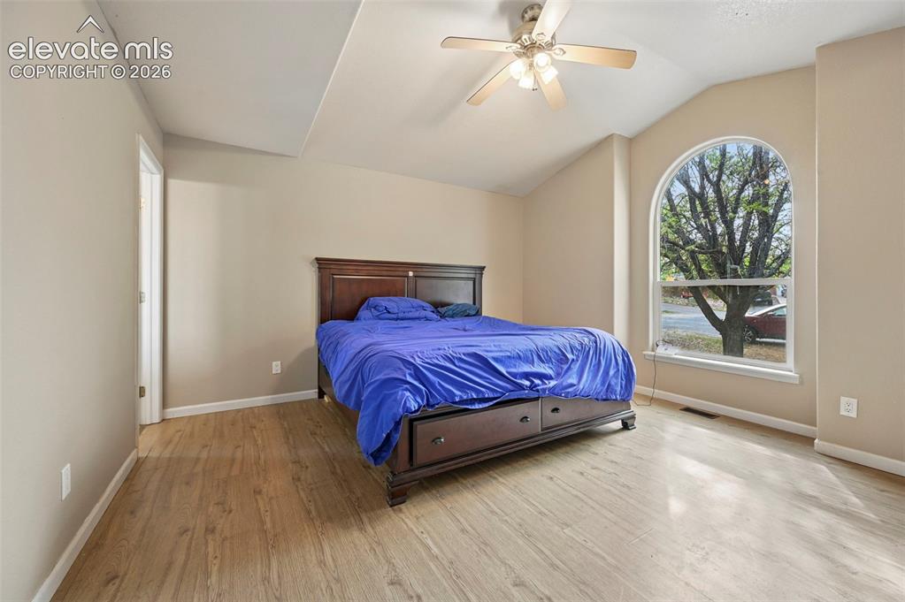 Image 28 of 32: Room featuring a vaulted ceiling with a ceiling fan, a large arched window,