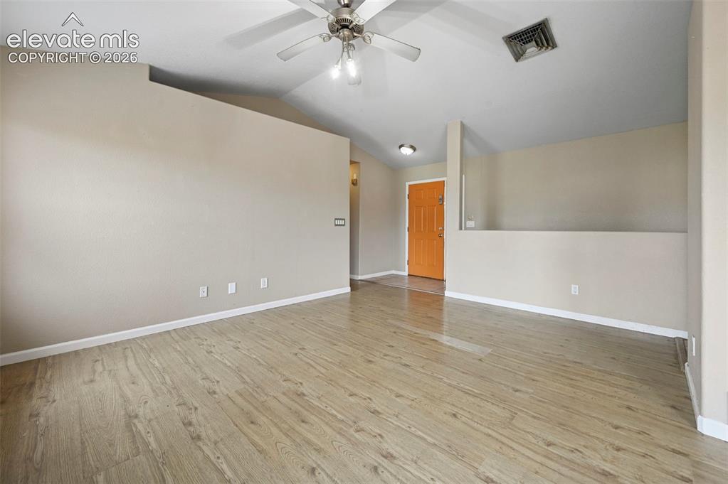 Image 32 of 32: Spacious room featuring wood-finish flooring, vaulted ceiling, and a ceilin