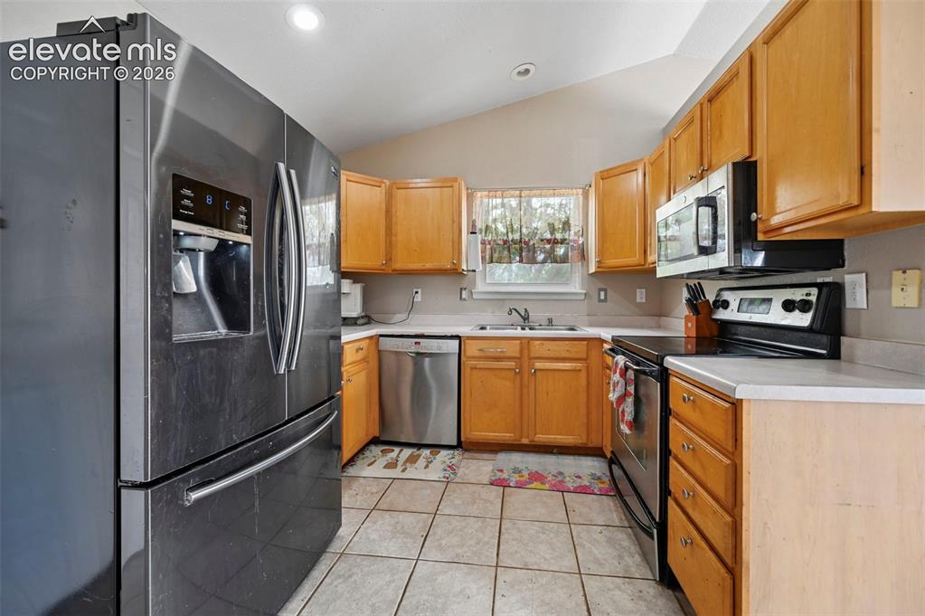 Image 5 of 32: Vaulted kitchen featuring tile flooring, light wood cabinetry, light-colore