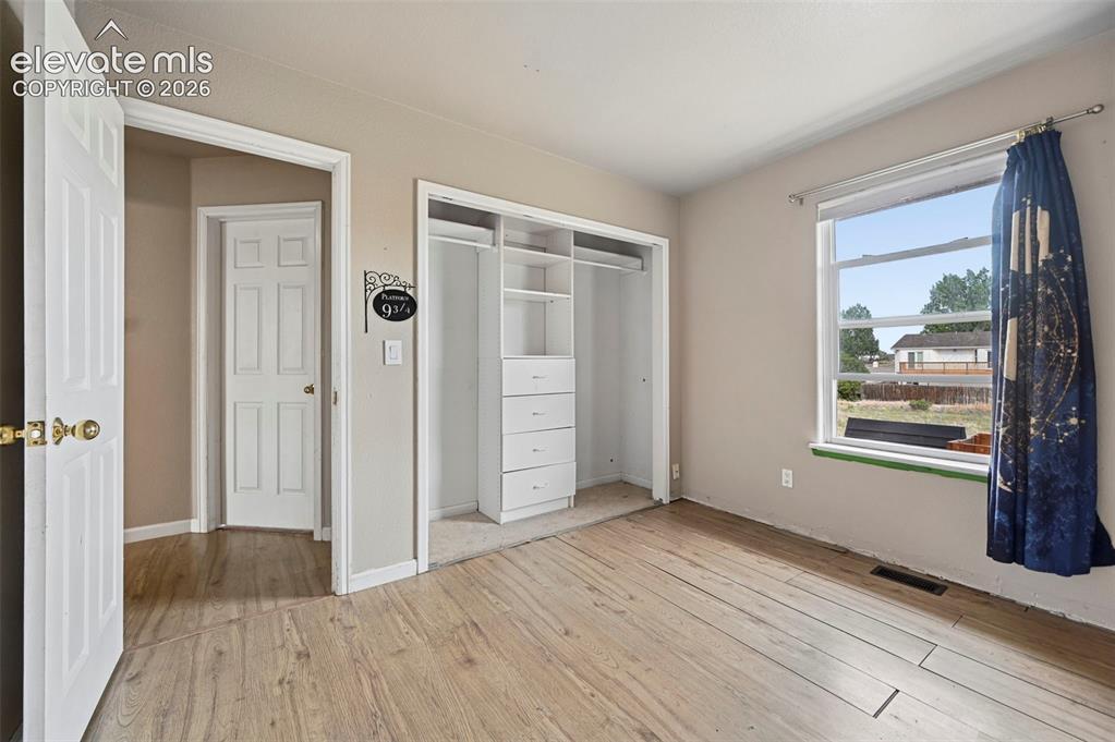 Image 7 of 32: Room featuring wood-finish flooring, neutral wall paint, and a built-in clo