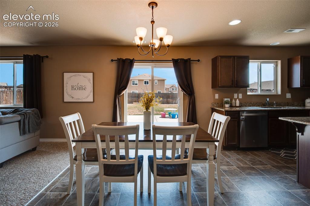 Image 12 of 37: Dining Area off the Kitchen with tile floor, a modern light fixture, and sl