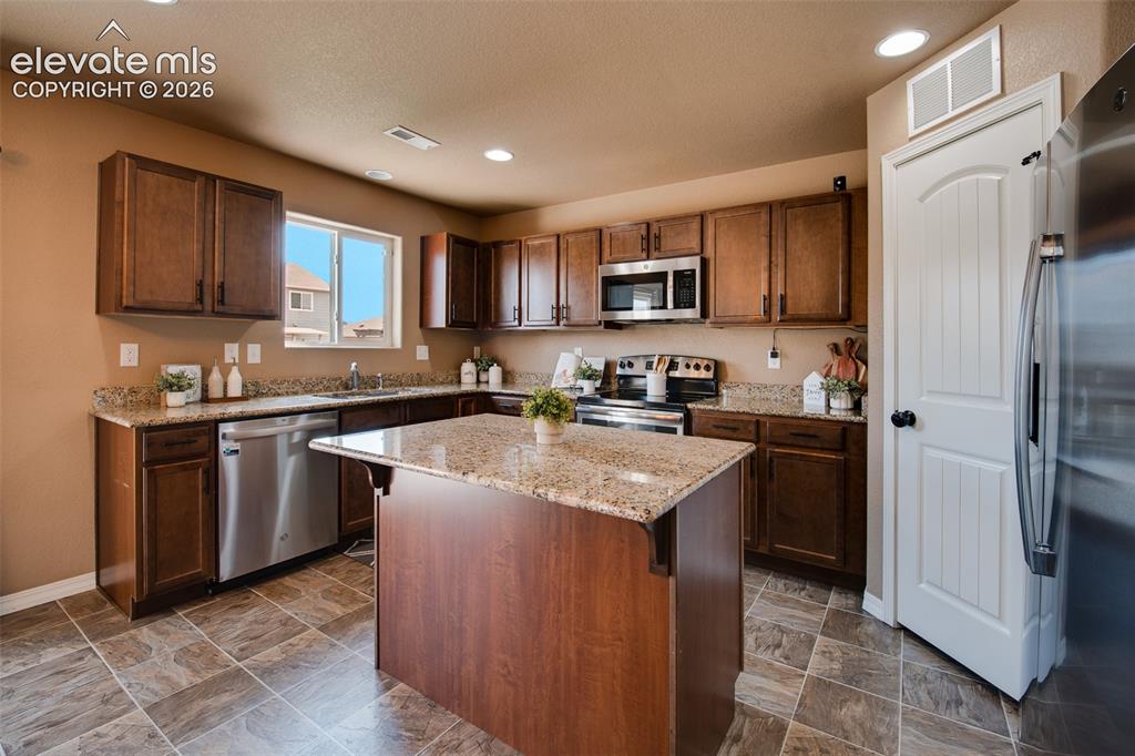Image 13 of 37: The Island Kitchen features a tile floor, breakfast bar, pantry, and wood c