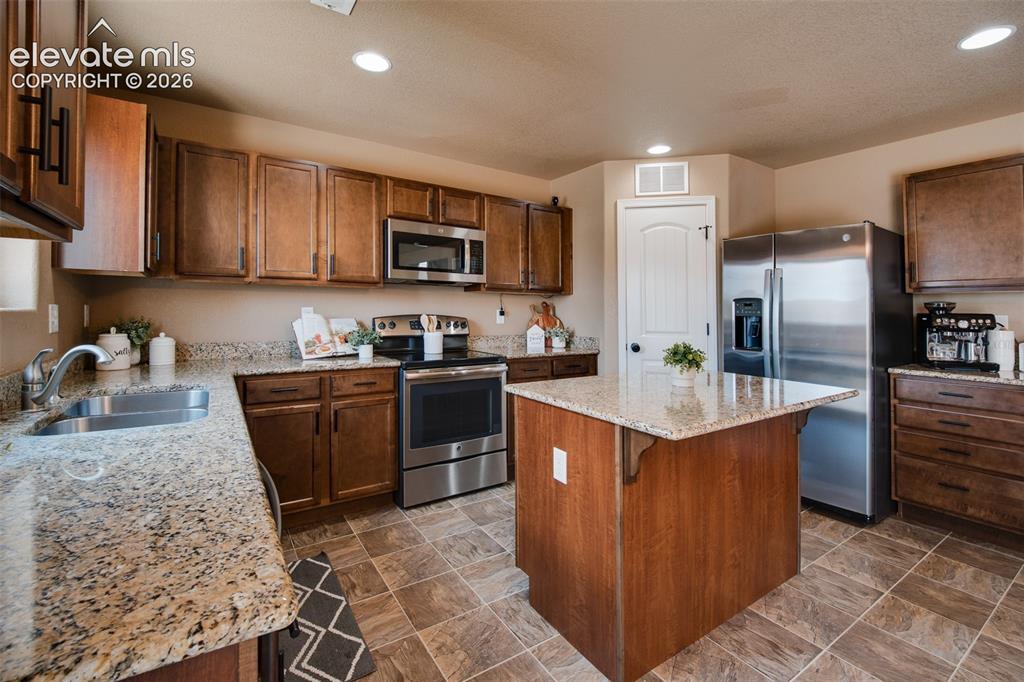 Image 14 of 37: Stainless steel appliances include a smooth top range oven, microwave, dish