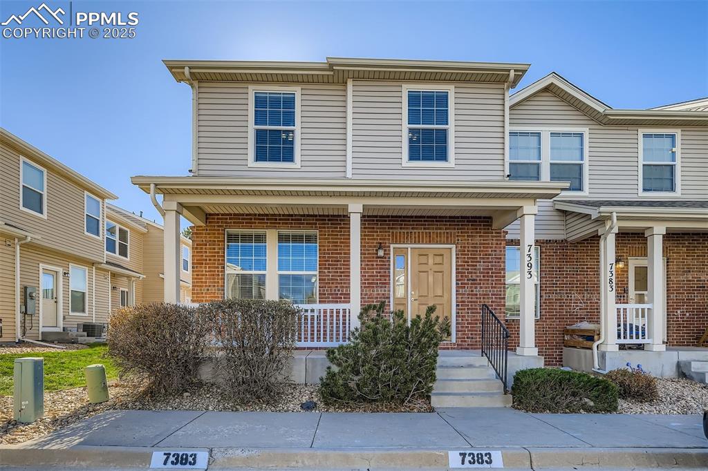Caption: End unit townhome with porch and brick and vinyl siding