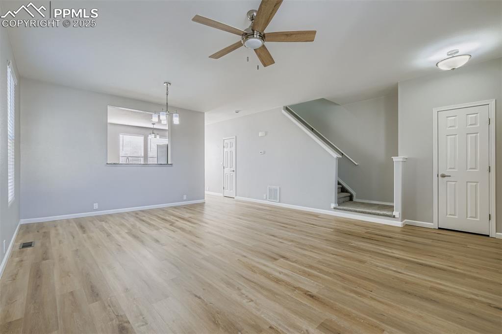 Image 4 of 22: Unfurnished living room featuring stairs, light wood-style floors, a ceilin