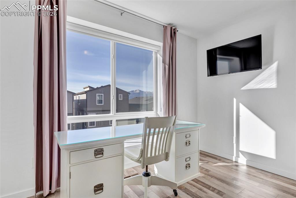 Image 7 of 39: Bedroom - LVP floors, Zebra window coverings, view of Pikes Peak