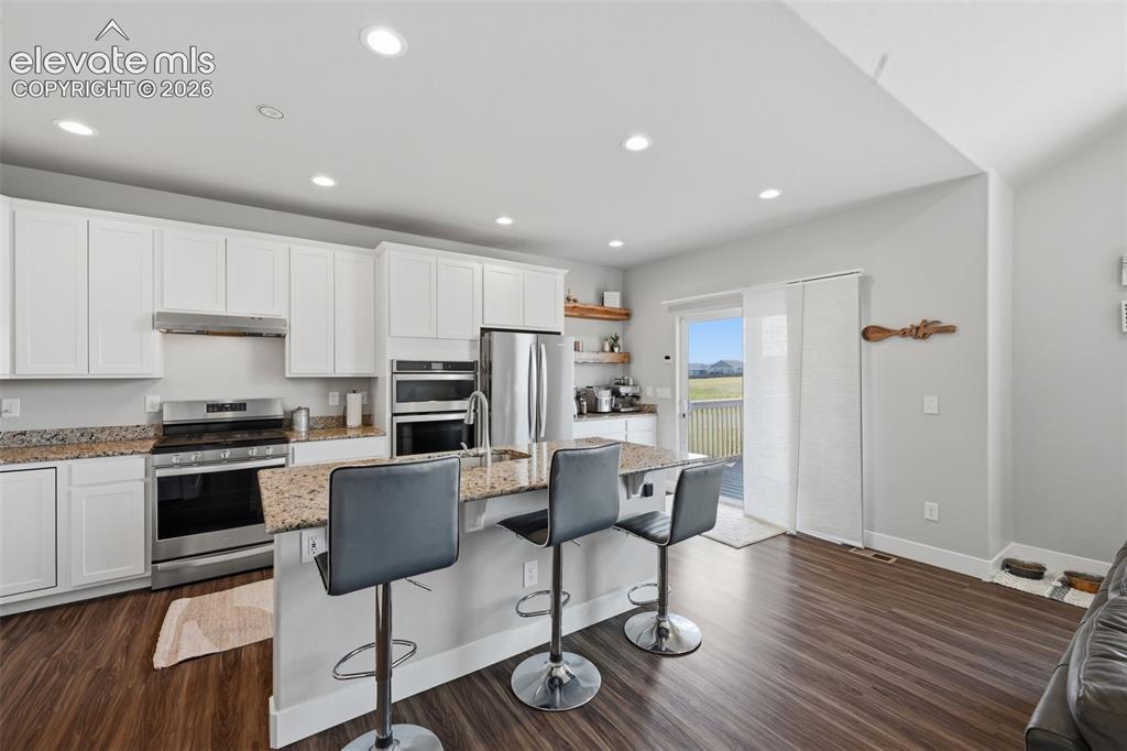 Image 14 of 31: Another view of the kitchen. Slab granite countertops really make this kitc