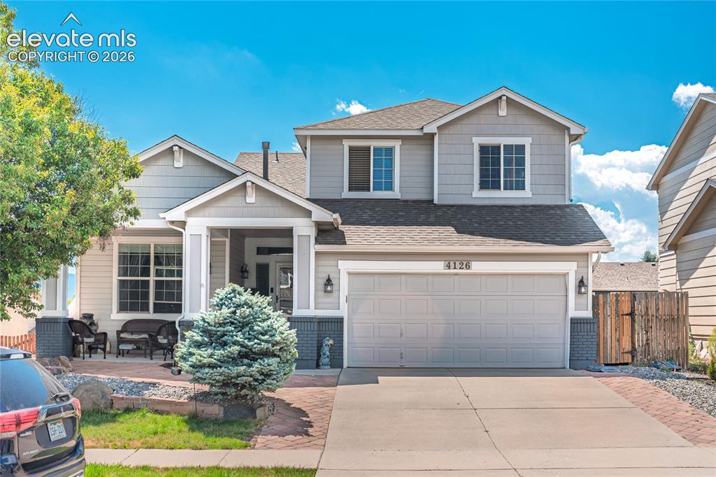 Caption: Two-story residence featuring a covered front porch, an attached garage, and a concrete driveway
