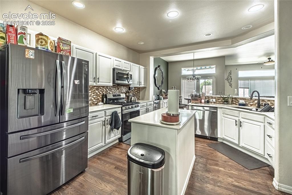Image 11 of 48: Kitchen featuring wood-finish flooring, white cabinetry, stainless steel ap