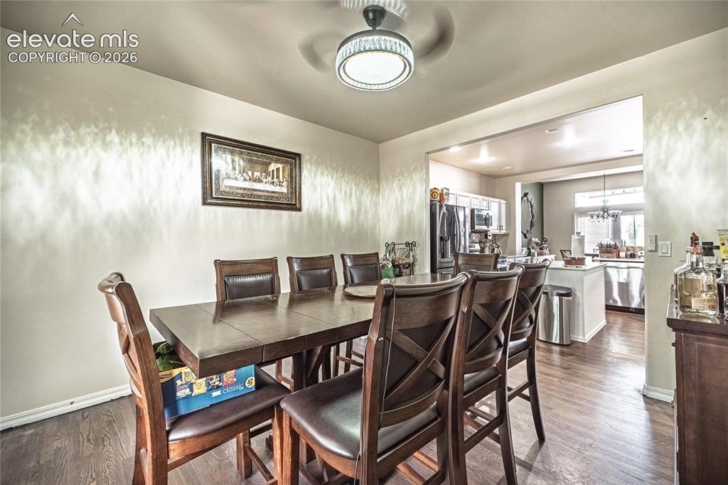 Image 13 of 48: Dining area with wood-finish flooring and a contemporary ceiling fan with i