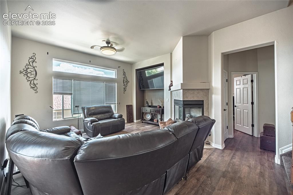 Image 15 of 48: Living area featuring wood-finish flooring, a ceiling fan, and a fireplace