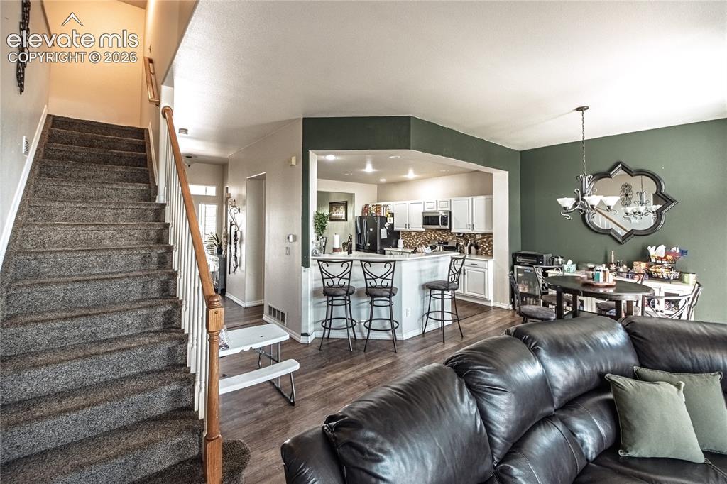 Image 17 of 48: Carpeted staircase with wood banister, wood-finish flooring, and a kitchen
