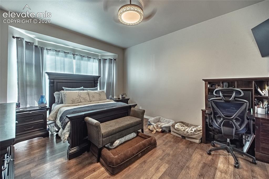 Image 21 of 48: Spacious room featuring wood-finish flooring and a bay window with blinds