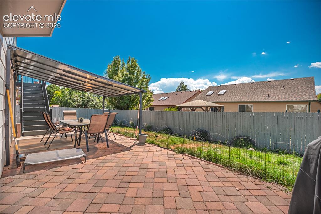 Image 40 of 48: Expansive brick paver patio featuring a covered outdoor area and a wooden p
