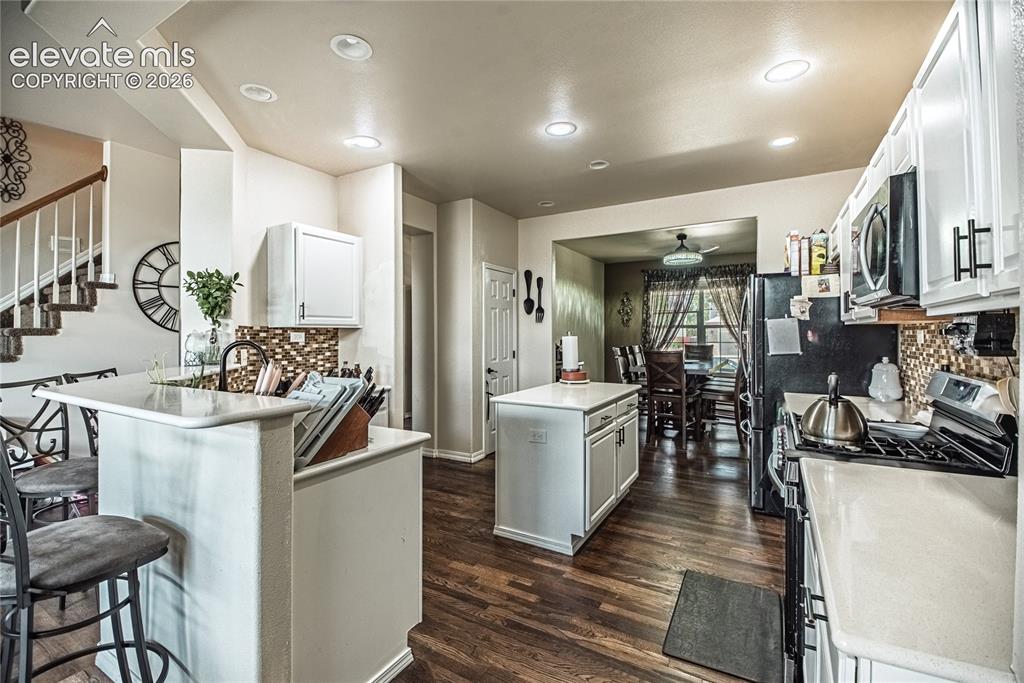 Image 8 of 48: Kitchen featuring white cabinetry, a center island, wood-finish flooring, a