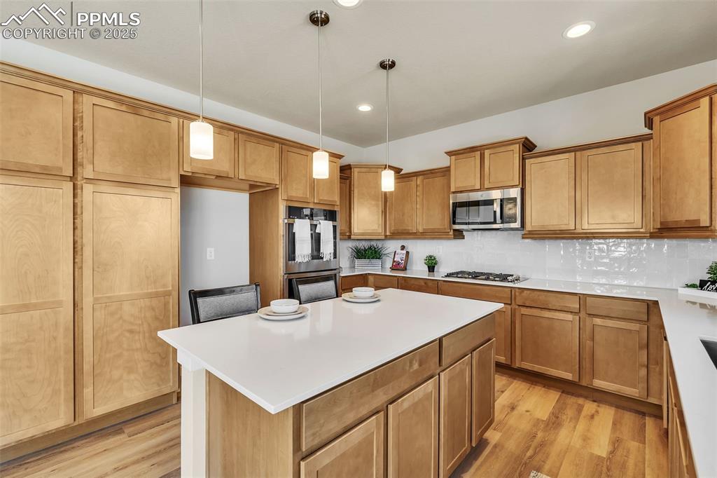 Image 15 of 46: Kitchen featuring a kitchen island, hanging light fixtures, light wood-type