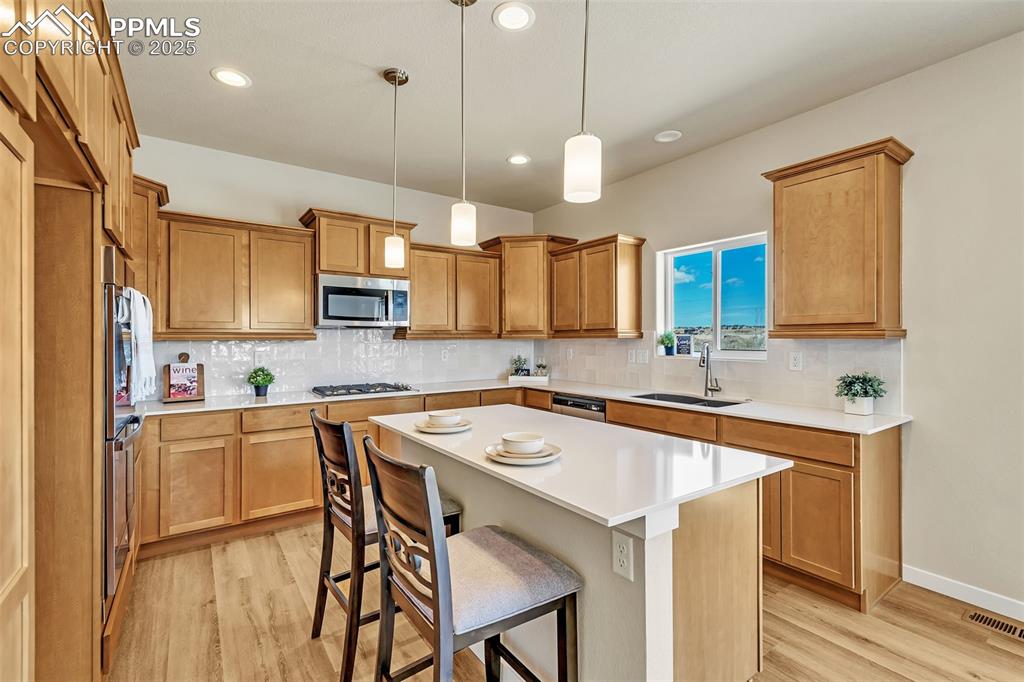 Image 16 of 46: Kitchen with a breakfast bar area, light wood-style flooring, pendant light