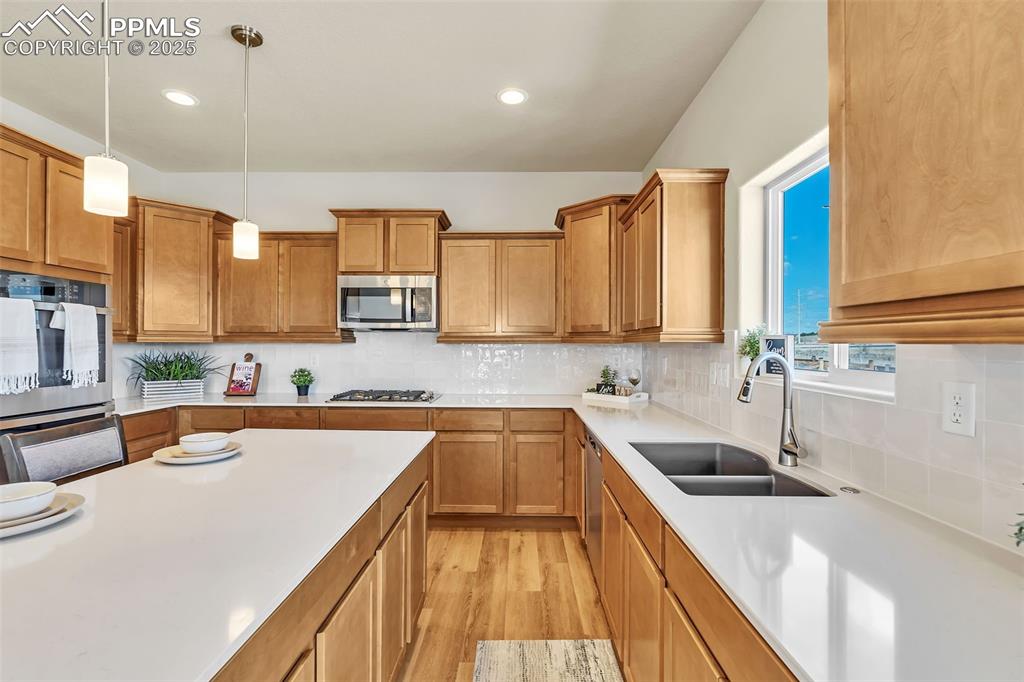 Image 17 of 46: Kitchen featuring brown cabinetry, light wood finished floors, appliances w