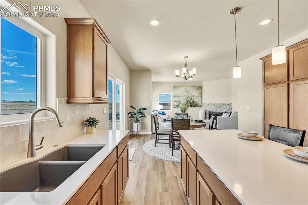 Image 18 of 46: Kitchen with tasteful backsplash, light wood-style flooring, brown cabinetr
