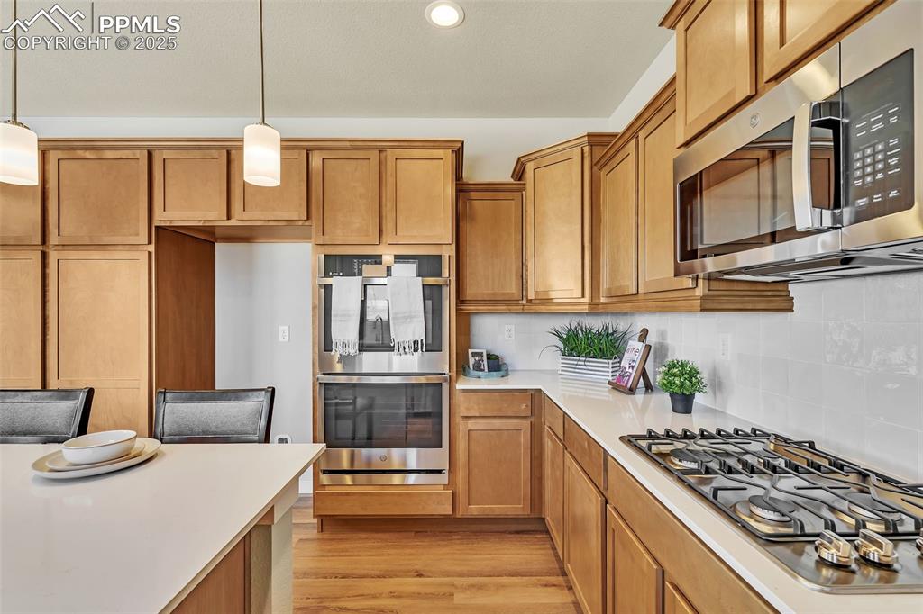 Image 19 of 46: Kitchen with appliances with stainless steel finishes, brown cabinetry, dec