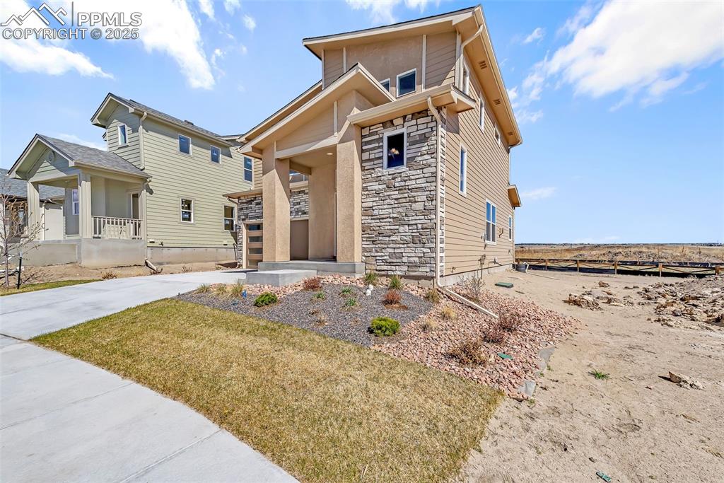 Image 2 of 46: View of front facade with stone siding, covered porch, and concrete drivewa