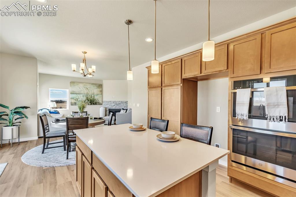 Image 20 of 46: Kitchen featuring stainless steel double oven, pendant lighting, light wood