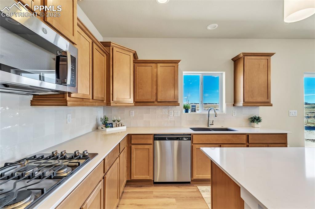 Image 21 of 46: Kitchen with stainless steel appliances, tasteful backsplash, brown cabinet
