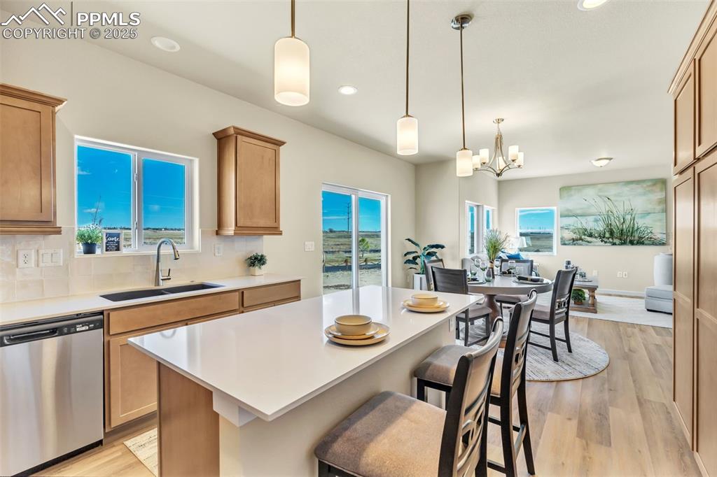 Image 22 of 46: Kitchen with dishwasher, light wood-type flooring, a breakfast bar area, ta