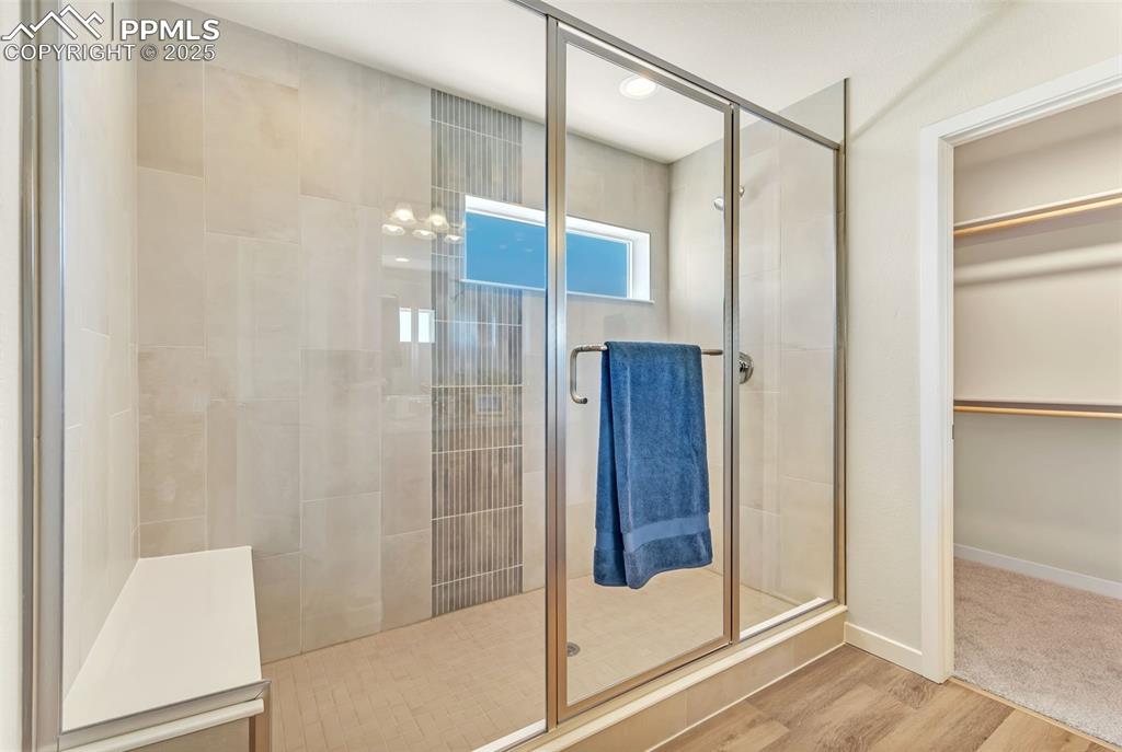 Image 29 of 46: Bathroom with a stall shower, wood finished floors, and a walk in closet