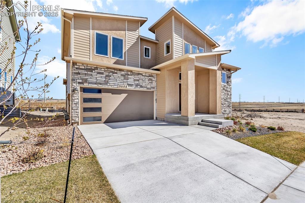 Image 3 of 46: Modern home with stone siding, concrete driveway, and an attached garage
