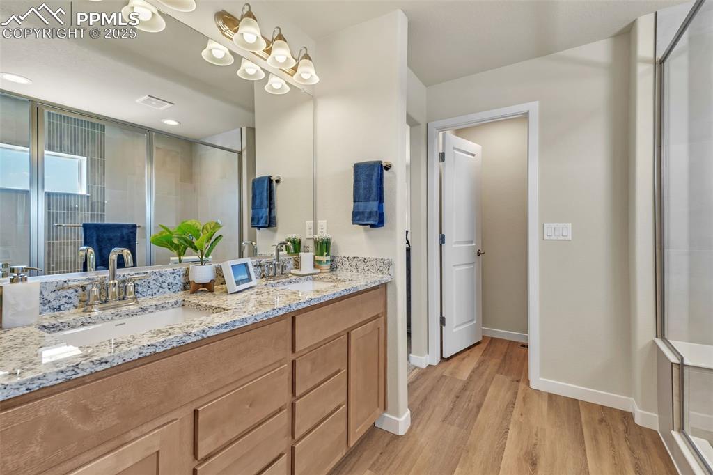 Image 33 of 46: Bathroom with a stall shower, double vanity, and light wood finished floors